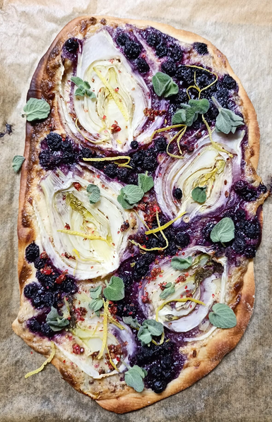 Der beschriebene Flammkuchen fertig gebacken und dekoriert. Der Fenchel ist so geschnitten, dass die Stücke aussehen wie Blüten.