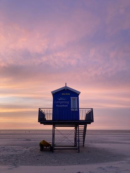 Ein blaues Rettungsschwimmerhäuschen im Sonnenuntergang am Strand von Langeoog.