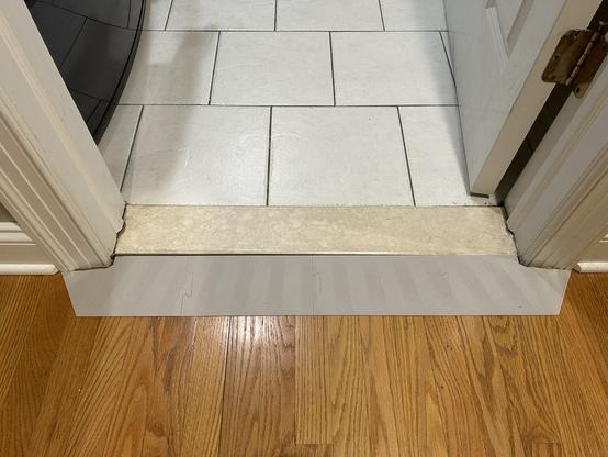 The 3D printed ramp is on the hallway floor.  It abuts a stone slab in the doorway that is about 20 millimeters higher than the hall floor.  
It extends to the outer edge of the door frame on both sides.
It is snug against the slab and does not quite touch the frame on the right, but on the left it only touches the frame, and there is a gap of about 3 millimeters between the ramp and the slab.