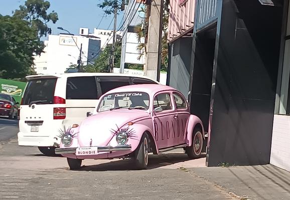 Ein rosa VW Käfer vor einem Geschäft in Asuncion. Die Scheinwerfer sind mit Augenwimpern verziert.