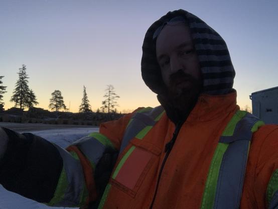 A large COs male with a bright red beard and reflective jacket offers out a hug