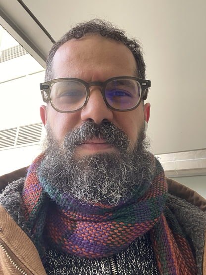 Selfie of me, slightly frowning, glasses foggy, frozen droplets of water on my beard.