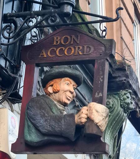 A carved wooden pub sign showing a man holding an overflowing tankard of beer.
