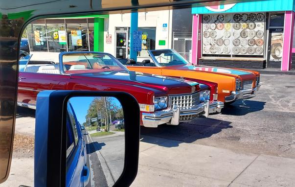 Two colorful convertible cars as seen out of the side window of my car while waiting at a stoplight.