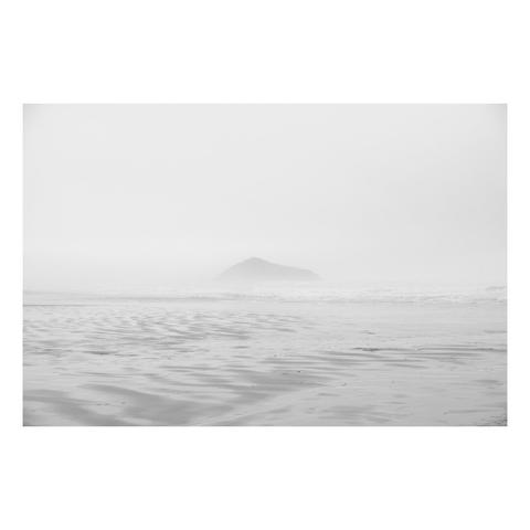 Pacific beach in the fog with no horizon line and a rock island peeking out