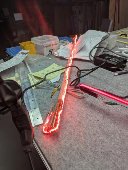 the crackle tube lit up with a bunch of crossed wires an alligator clips on the fancy felt table that I put stuff to sit for awhile (messy). Lets see how this runs for awhile. That red arc dances around really quickly. 22 torr of neon gas (atmosphere is about 755 torr). Vaudeville neon is also sitting here