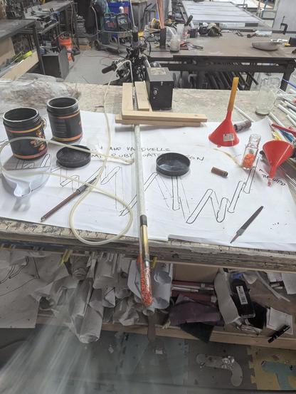 Crackle tube and work table after sealing the last electrode on (you can see my brass holder. The Trash and Vaudville pattern I made (in case of breakage) is underneath as well as various sorting bins an tools for the glass. the big black transformer at the end acts as a weight. I sealed the electrode on with a hand torch