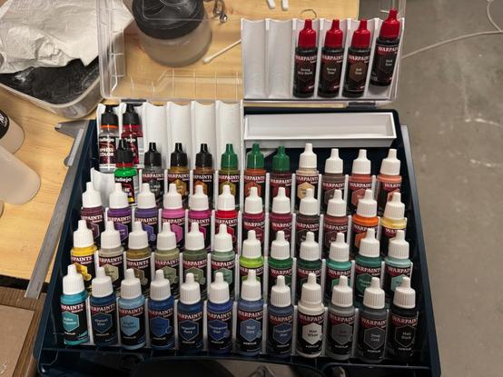 An Sortimo iBoxx72 with a range of Army Painter Warpaint Fanatic bottles inside it. The bottles are organised in a 3d printed storage system, allowing up to 60 bottles inside one case. In the upper right corner one of the storage segments is removed from the case to show the small hidden storage box underneath it.