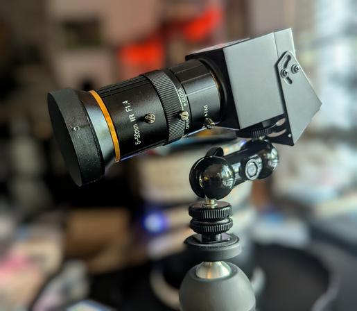ELP 4K 'webcam' with manual 5-50mm f1.4 zoom. 

The camera is just a little black cube attached to a tripod mount. The lens is 2-3 times the size of the camera body. There is a double ball pivot joint on the tripod positioned so that the CoG of the camera is over the tripod so the camera/lens weight won't tip it over.