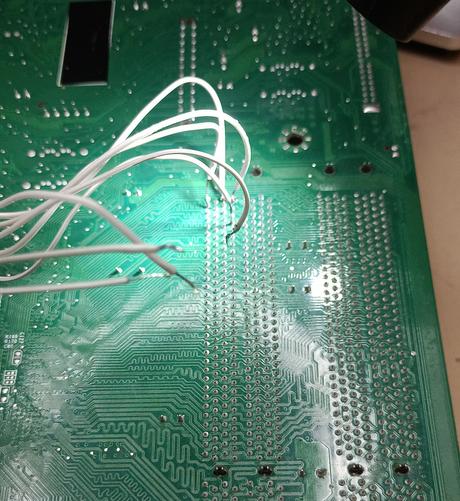Backside of a computer Mainboard with some wires soldered to its ram connector pins