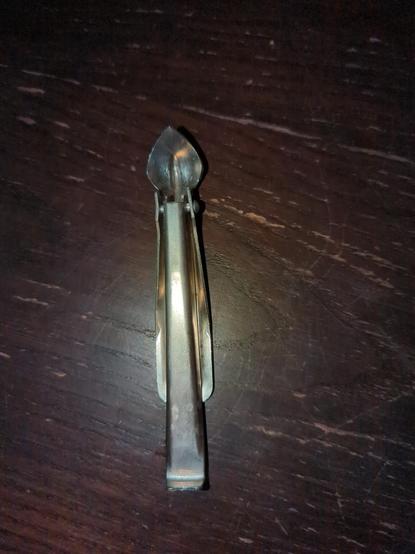 ein Metallteil mit einem Griffstück an dessen etwas wie eine gewölbte Spitze dran ist, als könnte man damit etwas ausschaben. 
im griff ist ein weiteres Metallstück beweglich angebracht, an dessen Ende ein flacher Teil abgewinkelt ist.