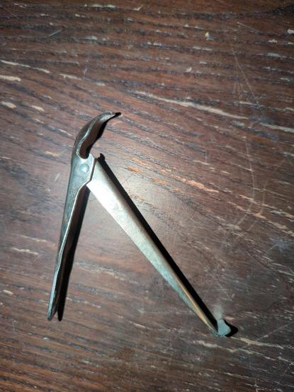 ein Metallteil mit einem Griffstück an dessen etwas wie eine gewölbte Spitze dran ist, als könnte man damit etwas ausschaben. 
im griff ist ein weiteres Metallstück beweglich angebracht, an dessen Ende ein flacher Teil abgewinkelt ist.