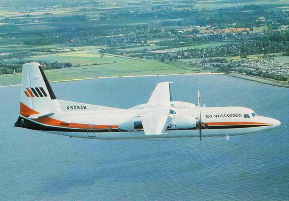 Prop plane is flying over a lake.