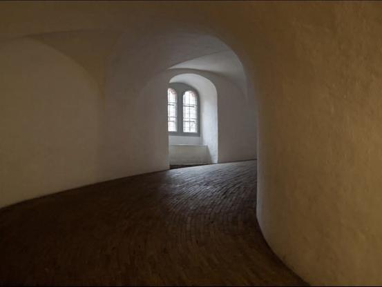 window on the left handside set into an arch within an arch. walkway going clockwise round and up