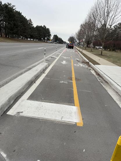 A picture of a police officers car parked in the bike lane in front of a bus stop on the side of a large divided 8 lane road.