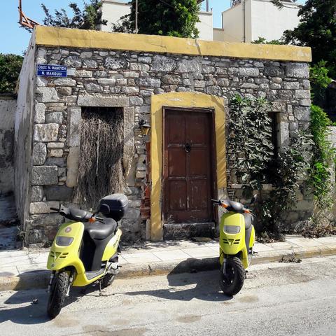 A derelict stone building with two yellow scooters parked outside.