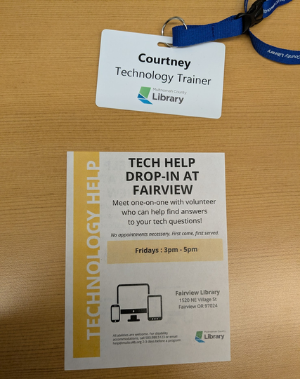 This image shows an ID badge for Courtney, a Technology Trainer at Multnomah County Library, attached to a blue lanyard. Below the badge is a flyer advertising "Tech Help Drop-in at Fairview" library, offering free one-on-one tech assistance on Fridays from 3-5pm, with device icons and location details displayed on a white and yellow designed layout.

(Description assisted by Claude AI.)