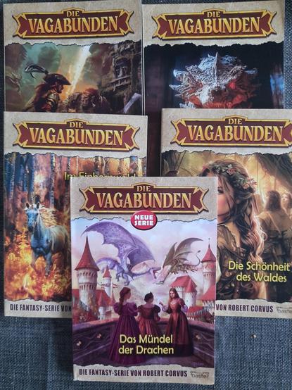 Cover von fünf bunten Fantasy Titeln "Die Vagabunden" mit Drachen und Burgen.