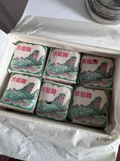 Tea wrapped in individual servings in paper packets with a two color faded print of the mountains in each one Chinese lettering in red says “shui shien-chung” the variety. there are six remaining if 12 in a tin box.
