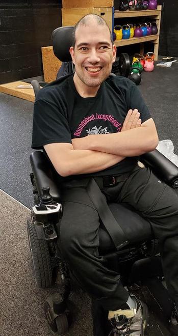 Medium close-up of a smiling young man in a wheelchair.