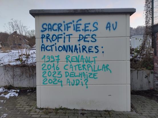 Graffiti au spray dans deux teintes de bleu, sur le béton gris clair, de 2 × 2 m environ.