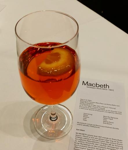 Ein Glas Aperol Spritz, daneben der programmzettel von Macbeth