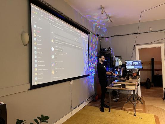 Cool dude in all black at a podium in front of a slide showing a chat stream