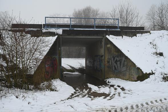 Überschwemmte Unterführung einer Eisenbahnlinie im Schnee