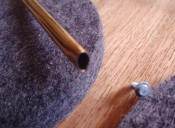 Rechts auf dem Tisch eine Spezialschraube, damit Du Dein Recht auf Reparatur nicht ausüben kannst.
Daneben die Lösung.  Links ein Metall-Trinkhalm. Er wird mit der Zange oder Hammer oval gemacht.
Damit lassen sich die Schrauben leicht rausdrehen.