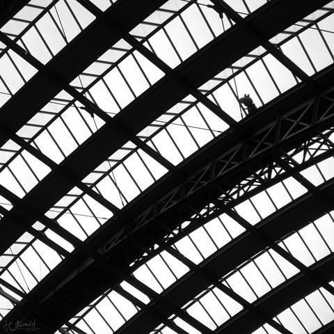 View of the roof of Frankfurt Central Station. You can see the steel roof construction running diagonally across the picture and the rows of windows, which are also arranged in arches. Peppa Pig seems to be looking in through one of the windows at the top right. You can see her small silhouette.