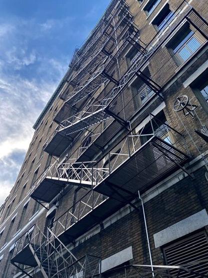 A fire escape zig zags up the vertical face of a building