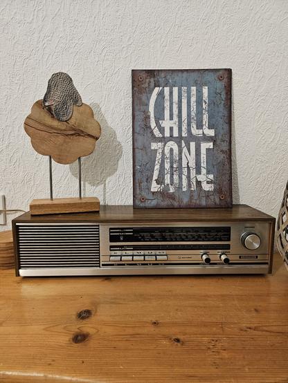 Ein altes Radiogerät aus den 70ern, darauf ein Blechschild mit der Aufschrift "Chill Zone" und eine Skulptur eines Schafes