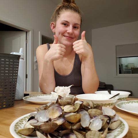 Cassidy giving 2 thumbs up at dining bar table & plate of empty clam shells in front