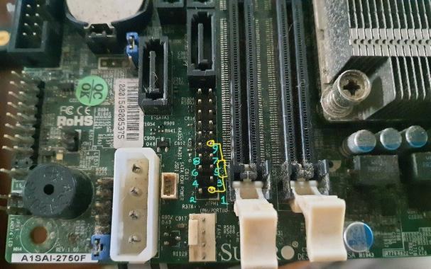 Close-up of JTPM1 which is a standard 100mil 2×10 pin header with pin 4 removed.  The pins where the resistor are to go (judging from the Imgur post) are marked.