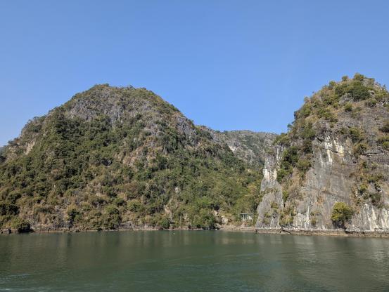 Lush vegetation clings to the craggy limestone cliffs, creating a dramatic landscape.
