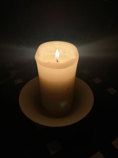 a closeup of a burning fat white survival candle that will burn for days.