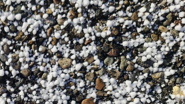Schneegraupel auf Strassenbelag, der Kornsteinchen selber grösse hat