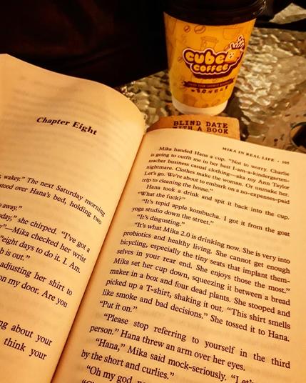 an opened book with a coffee on the side.