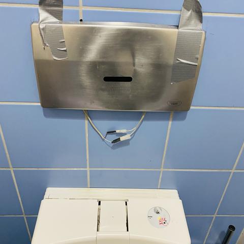 zeigt ein autobahn klo an der A7 dessen infrarot detectorlogik an der wand mit gaffa tape befestigt wurde und dessen elektronische kabel unten raushaengen.