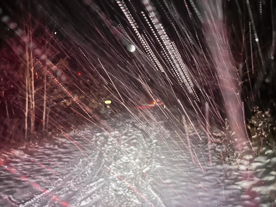 Winter conditions and heavy snow fall on a path marked with tire marks.
