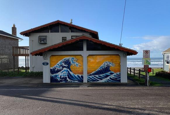 On a beach house, the garage doors are painted in the style of Katsushika Hokusai's "The Great Wave" painting, with a warm golden background.
