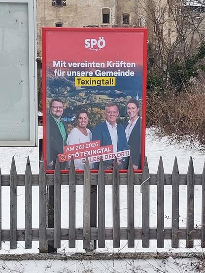 An einem Gartenzaun ist ein Plakatständer mit einem Wahlplakat der SPÖ Texingtal befestigt. Auf dem Plakat steht der Satz Mit vereinten Kräften für unsere Gemeinde Texingtal!
Darunter sind die vier Kandidaten zu sehen, zwei Männer und zwei Frauen. 
Am Boden des Plakates steht der Satz Am 26.1.2025 X SPÖ Texingtal und der Slogan Es lebe der Ort!