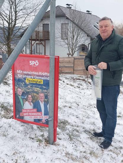 Ein Mann in Winterjacke steht neben einem Plakatständer mit einem Wahlplakat der SPÖ Texingtal und blickt in die Kamera. Auf dem Plakat steht der Satz Mit vereinten Kräften für unsere Gemeinde Texingtal!
Darunter sind die vier Kandidaten zu sehen, zwei Männer und zwei Frauen. 
Am Boden des Plakates steht der Satz Am 26.1.2025 X SPÖ Texingtal und der Slogan Es lebe der Ort!