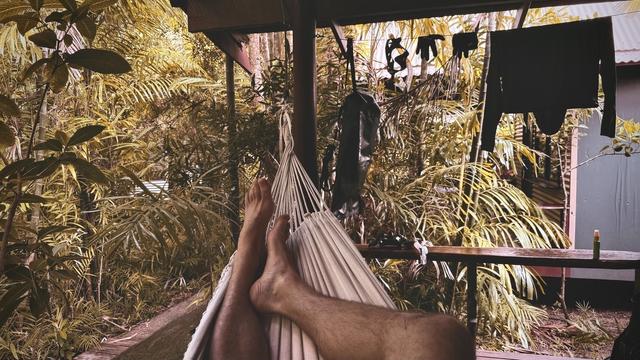 POV from lying inside a hammock, jungle scenery on the left, various snorkel gear hung up to dry on the right