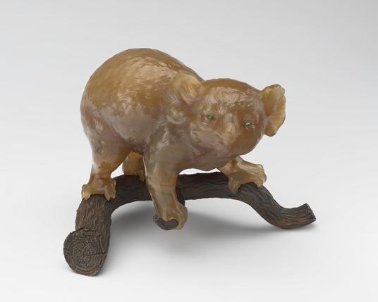 "A koala bear, carved in honey-coloured agate with cabochon emerald eyes, poised on a chased silver branch."