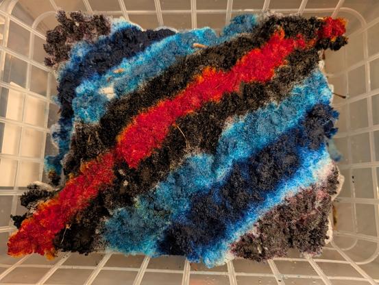 Top-down photo of rainbow colored snow piled up in a plastic bin over a big plastic grate.

Color order: indigo, blue, cyan, black, orange-red, black, cyan, blue, indigo