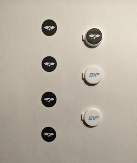 A printer paper page with a vertical column up 4 ShmooCon logos (solid black circle with white Shmoo face). To the right are 3 SIPmask valve covers: the top one has a ShmooCon logo glued on; the bottom two have the original SIP logo.