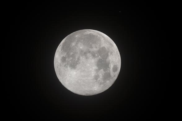 Der Vollmond am dunklen Nachthimmel, rechts oberhalb ein orangener Punkt