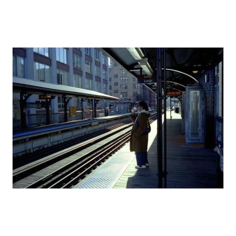 Individual standing on the platform of The Loop in Chicago drinking a beverage, while waiting for their train to arrive.