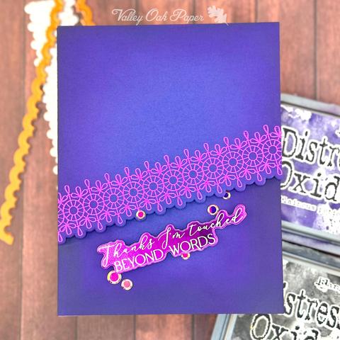 A dark purple greeting card with light purple foiled lace pattern across it. The greeting reads "Thanks, I'm touched beyond words."